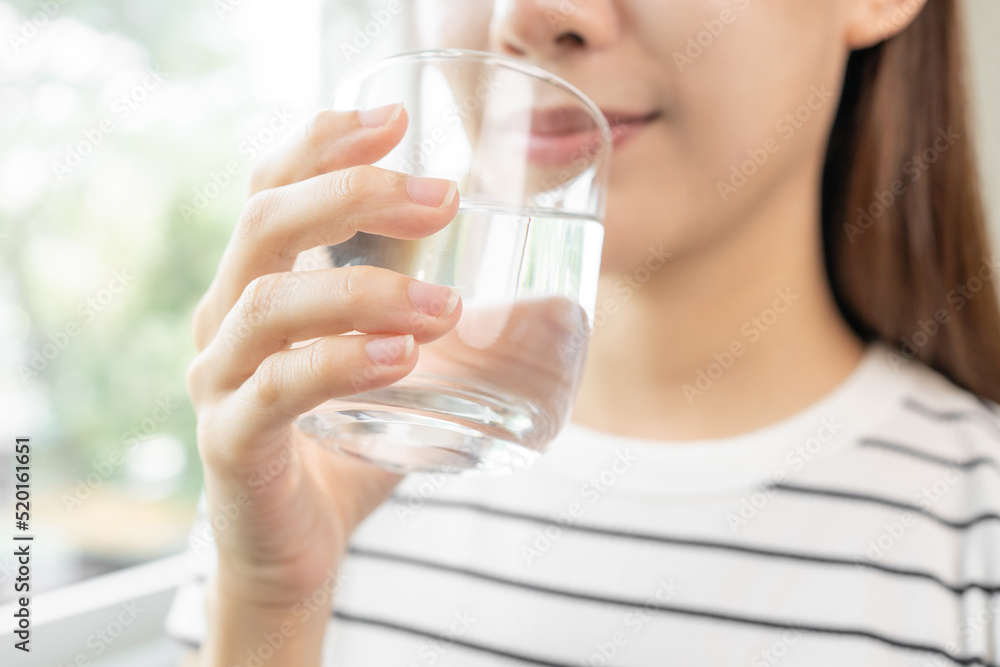 Happy beautiful, asian young woman, girl drinking, sip fresh glass of water for hydration of body, holding transparent glass in her hand, thirsty at home. Health care, healthy lifestyle concept. Happy beautiful, asian young woman, girl drinking, sip fresh glass of water for hydration of body, holding transparent glass in her hand, thirsty at home. Health care, healthy lifestyle concept.
