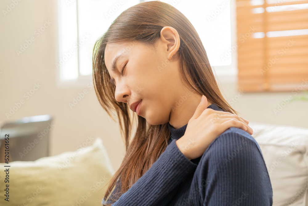 Body muscles stiff problem, asian young attractive woman, girl pain with back pain ache from work, holding massaging rubbing shoulder hurt or sore, painful sitting on sofa at home. Healthcare people. Body muscles stiff problem, asian young attractive woman, girl pain with back pain ache from work, holding massaging rubbing shoulder hurt or sore, painful sitting on sofa at home. Healthcare people.