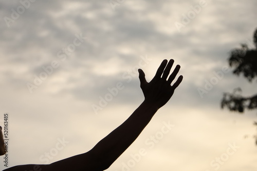 a back hand with beautiful sunset sky in the background symbolizes a person that reaching a dream as high as the sky