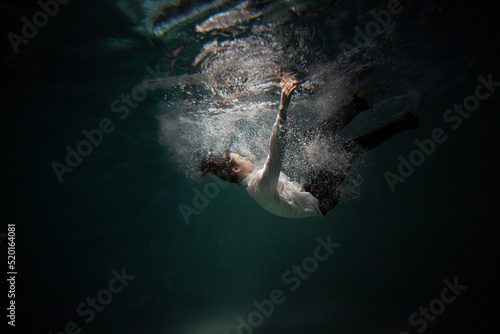 Tableau sur toile Beautiful underwater shooting, guy in white shirt and pants has fallen under the water and drowning