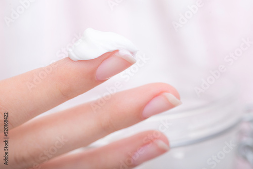 Young woman using moisturizer cream on her hands to take care of her skin