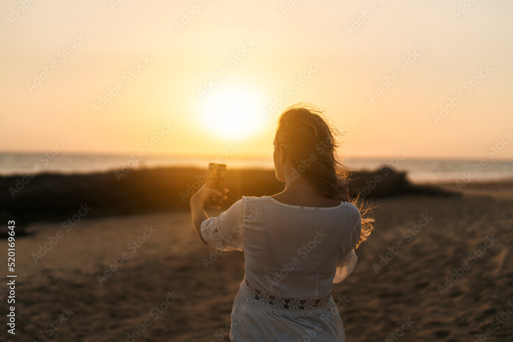 Chica joven con pelo largo haciendose fotos al atardecer con smartphone Chica joven con pelo largo haciendose fotos al atardecer con smartphone
