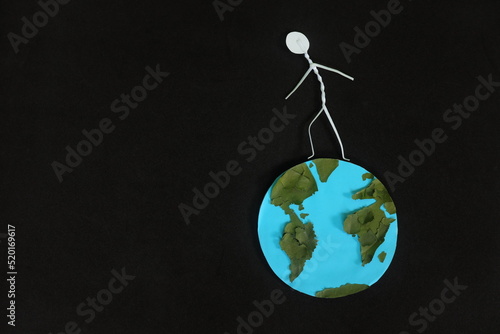 Human stick figure walking or running on top of planet earth in dark black background. World exploration concept. photo