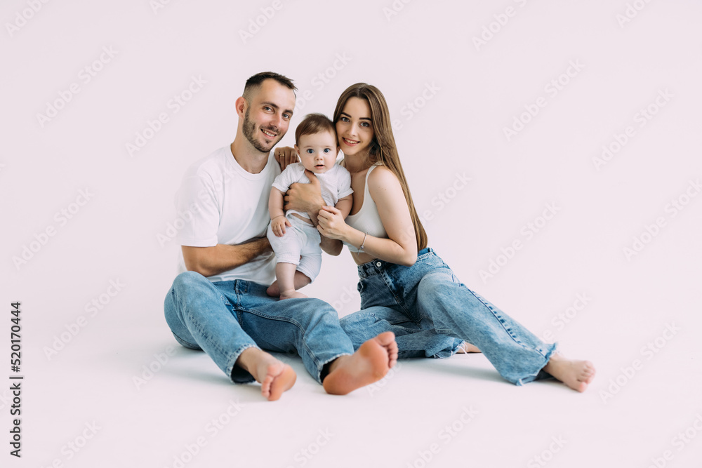 Family portrait of happy smiling mother, father playing on the floor with baby over white background Family portrait of happy smiling mother, father playing on the floor with baby over white background