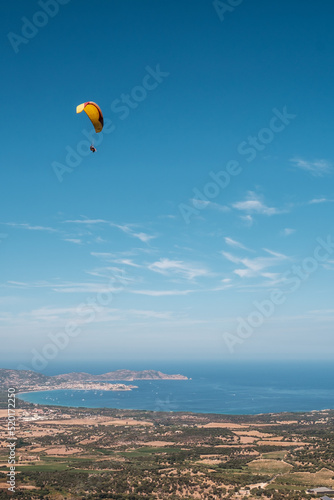 A tandem paraglider flies over the bay of Calvi in the Balagne region of Corsica