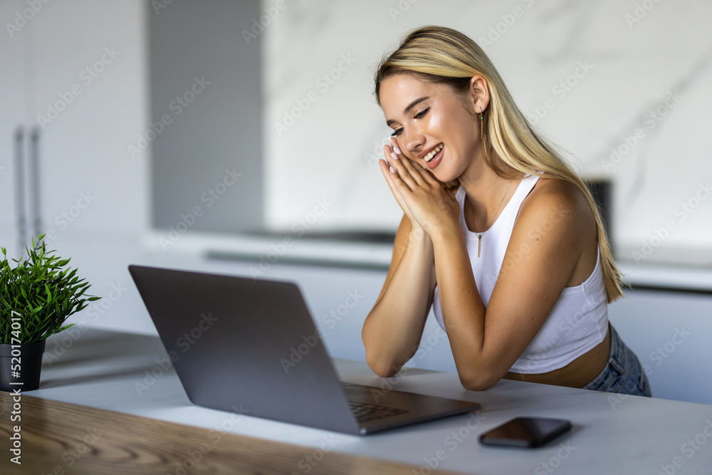 Fototapeta premium Cute smiling woman using laptop at home. Student girl working on computer. Online shopping, work from home, freelance, online learning, studying, lockdown concept. Distance education