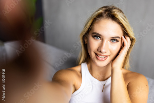 Pretty woman sitting on her sofa taking a picture of herself at home in the sitting room