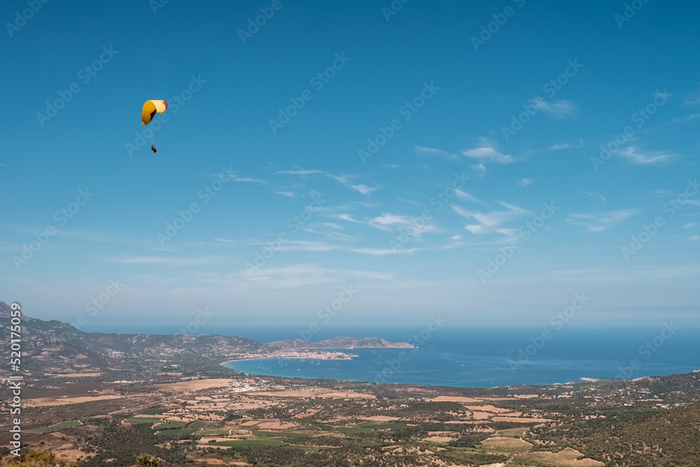 A tandem paraglider flies over the bay of Calvi in the Balagne region of Corsica A tandem paraglider flies over the bay of Calvi in the Balagne region of Corsica