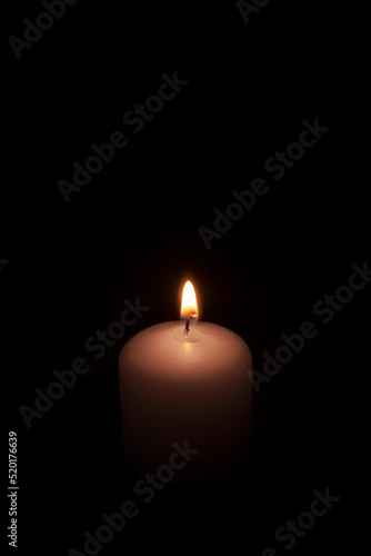 Burning wax candle on a black background