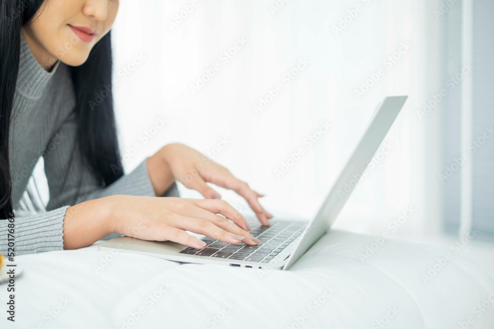 Fototapeta premium Beautiful asian eat show pizza and cola drink on bed. Happy woman sitting eating fast food. Lovely young working on laptop from home hand holding with junk food and soft drink showing. out of focus.