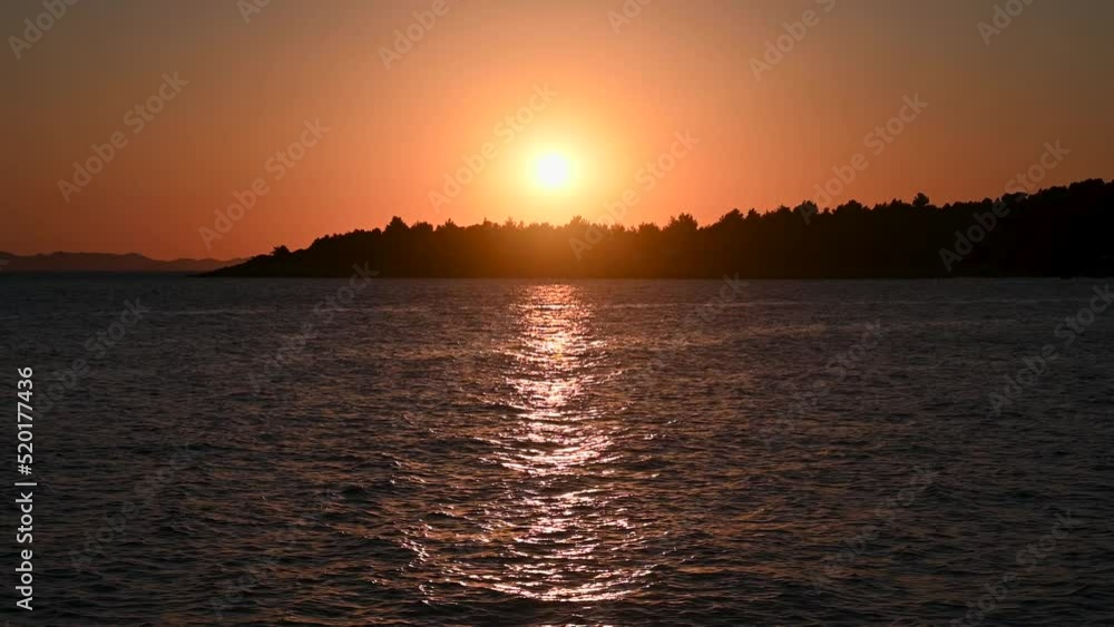 Golden sunset at the sea with soft waves. Tropical sunset. Seascape and shore. Sun going down in orange sky over horizon. Silhouette of a island. Golden sunset at the sea with soft waves. Tropical sunset. Seascape and shore. Sun going down in orange sky over horizon. Silhouette of a island.