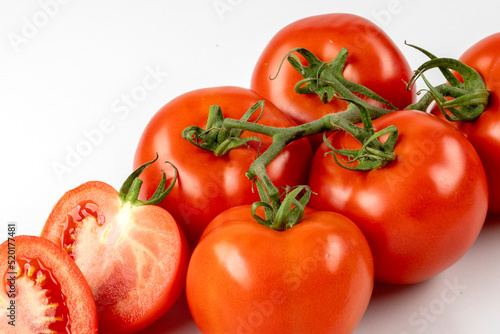 Six red fresh tomatoes on a branch and two half tomatoes isolated on white background. Fresh tomatoes on white background.