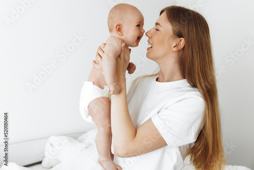 joyful mother with a cute little baby in her arms, Home portrait of a newborn with mother on the bed