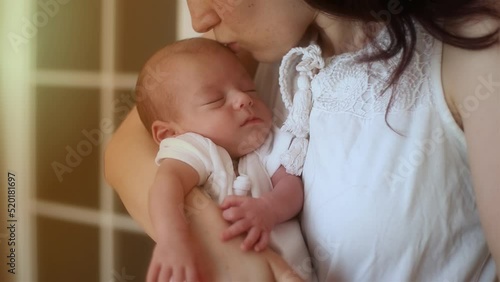 mother holding in her arms and kissing her newborn baby