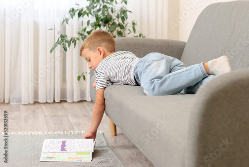 boy leafing through a book lying on the couch