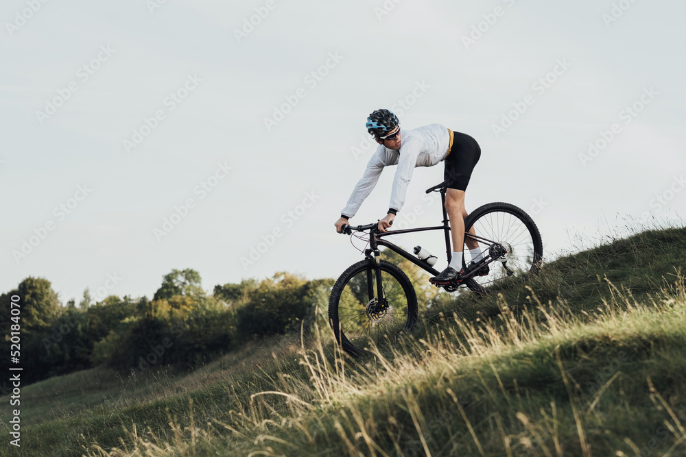 Professional Cyclist Descends a Slope on His Mountain Bike, Sportsman Going Down from Hill on Bicycle, Copy Space