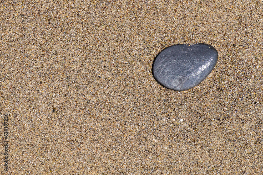 Obraz premium A small stone rounded by the erosion of sand and waves