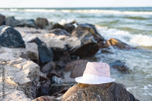 The hat lies on the stones near the sea shore under the summer setting sun
