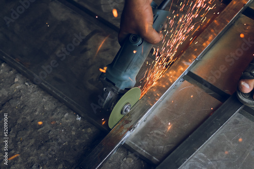 Worker cutting metal frame with hand cutter, disk cutter with sparks