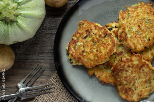 gebratene Reibekuchen aus Zucchini und Kartoffel auf Tisch aus Holz