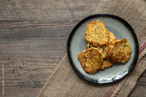 gebratene Reibekuchen aus Zucchini und Kartoffel auf Tisch aus Holz
