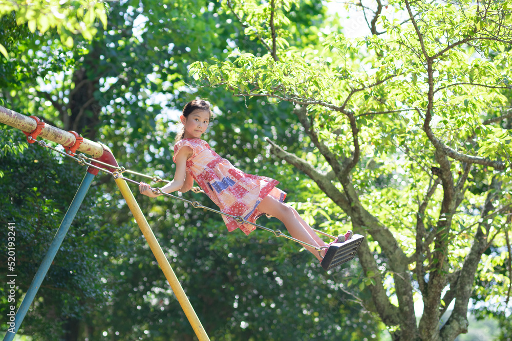 夏の公園でブランコで遊ぶ少女