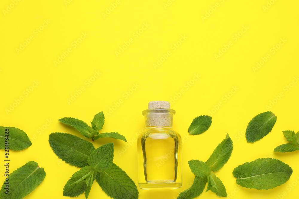 Bottle of essential oil and mint on yellow background, flat lay. Space for text Bottle of essential oil and mint on yellow background, flat lay. Space for text