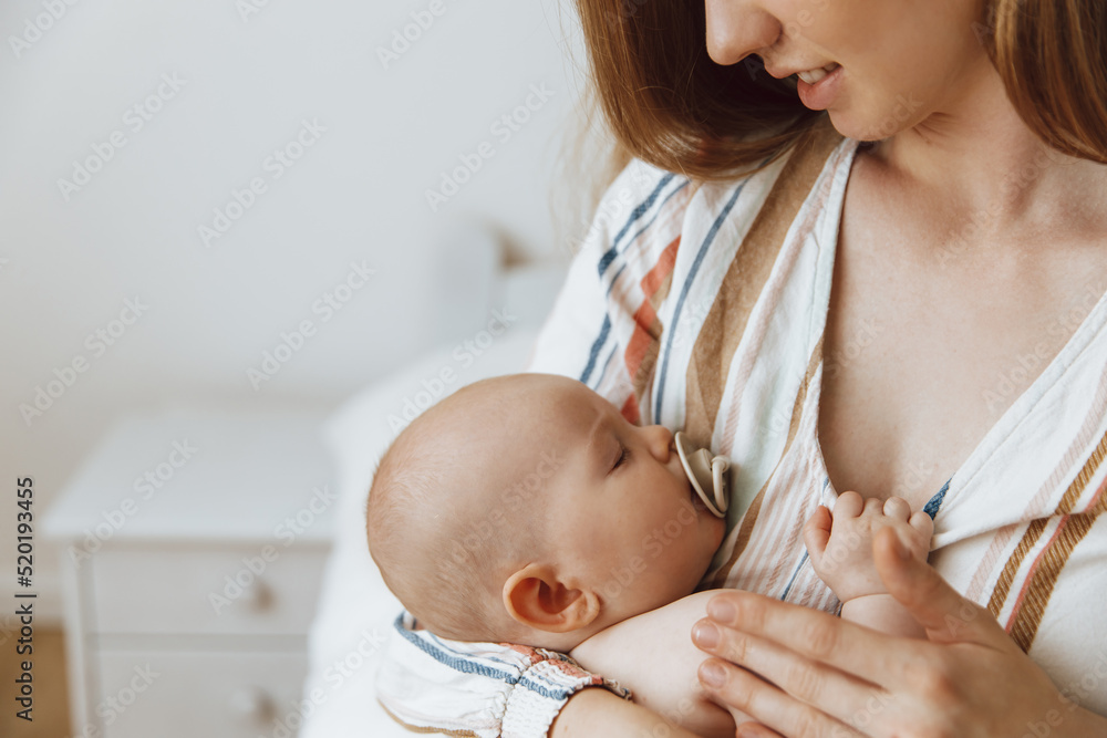 Loving mother takes care of her newborn baby at home. Portrait of ...