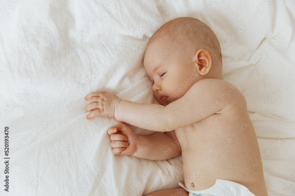 little baby sleeps peacefully, lying on his side in bed indoors, relaxing during his daytime nap with his eyes closed little baby sleeps peacefully, lying on his side in bed indoors, relaxing during his daytime nap with his eyes closed