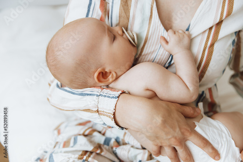 Loving mother takes care of her newborn baby at home. Portrait of a happy mother holding a sleeping baby in her arms