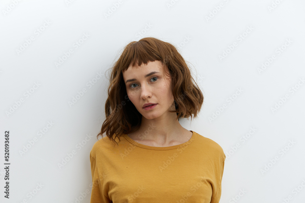 a beautiful, attractive, red-haired, relaxed woman poses standing in a yellow T-shirt on a white background and looks affably into the camera with pleasure a beautiful, attractive, red-haired, relaxed woman poses standing in a yellow T-shirt on a white background and looks affably into the camera with pleasure