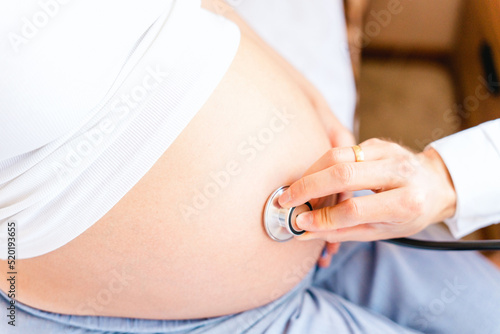 Pregnant consult doctor. Medical clinic for pregnancy consultant. Doctor examining pregnancy woman belly holding stethoscope. Concept of pregnancy, maternity, expectation for baby birth.