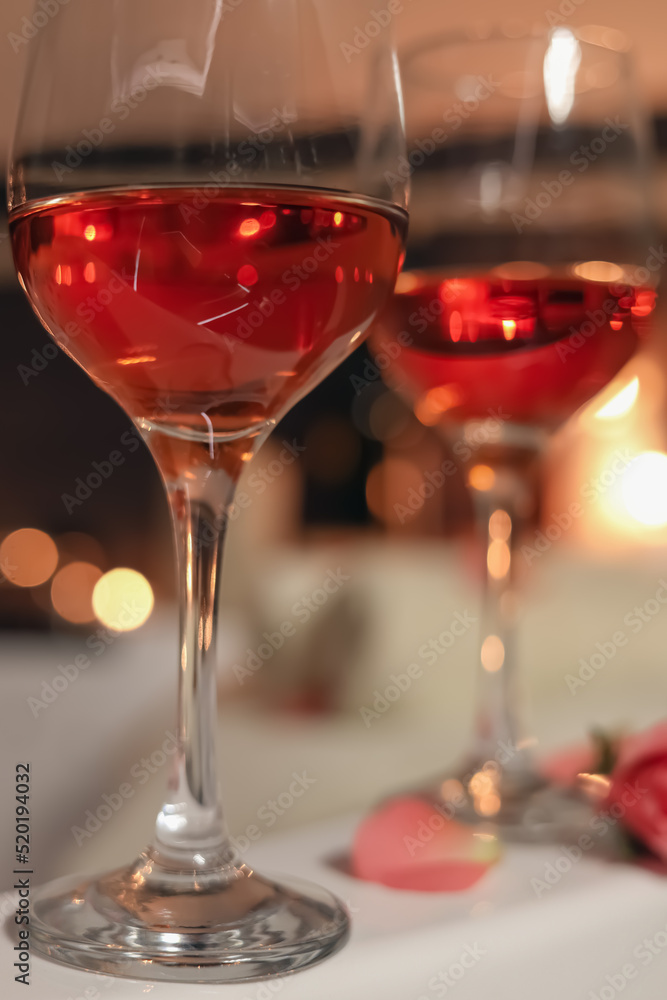 Wine in glasses on edge of bath indoors, closeup. Romantic atmosphere Wine in glasses on edge of bath indoors, closeup. Romantic atmosphere