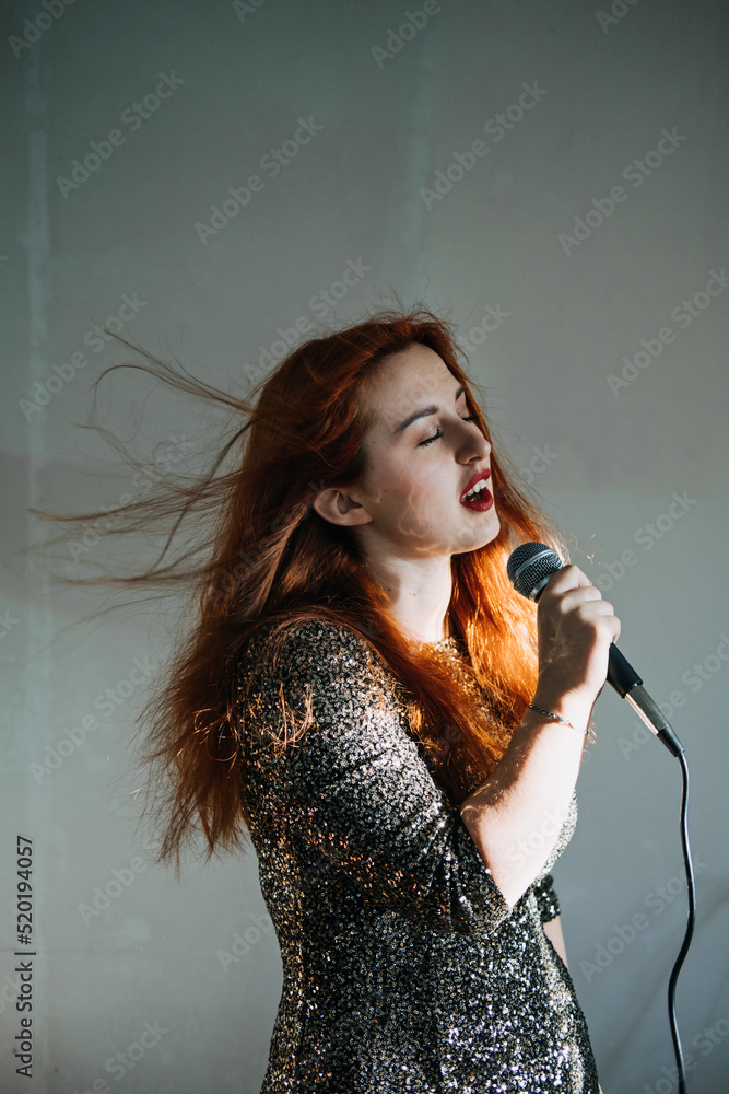 Portrait of redhead female singer woman in sparkly evening dress holding microphone Portrait of redhead female singer woman in sparkly evening dress holding microphone