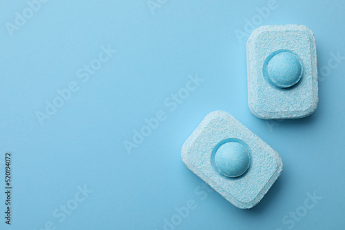 Water softener tablets on light blue background, flat lay. Space for text