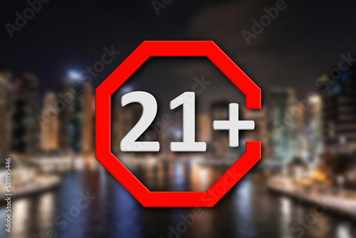 Age limit sign 21+ years and blurred view of night city