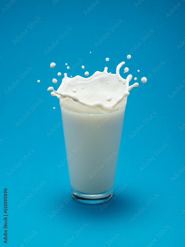 Milk splash in shape of crown in milk glass isolated on blue background.