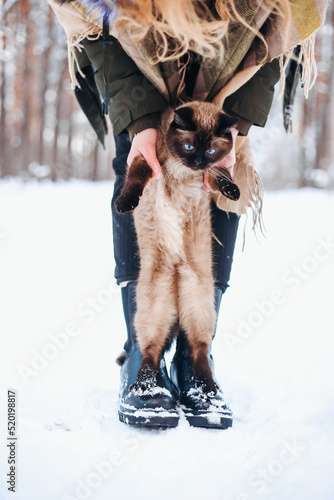 Girl woman and cat sitting on her shoulder in snowy winter forest