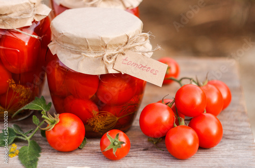 Jars with homemade pickled cherry tomatoes and a tag with text Tomatoes. Selective focus