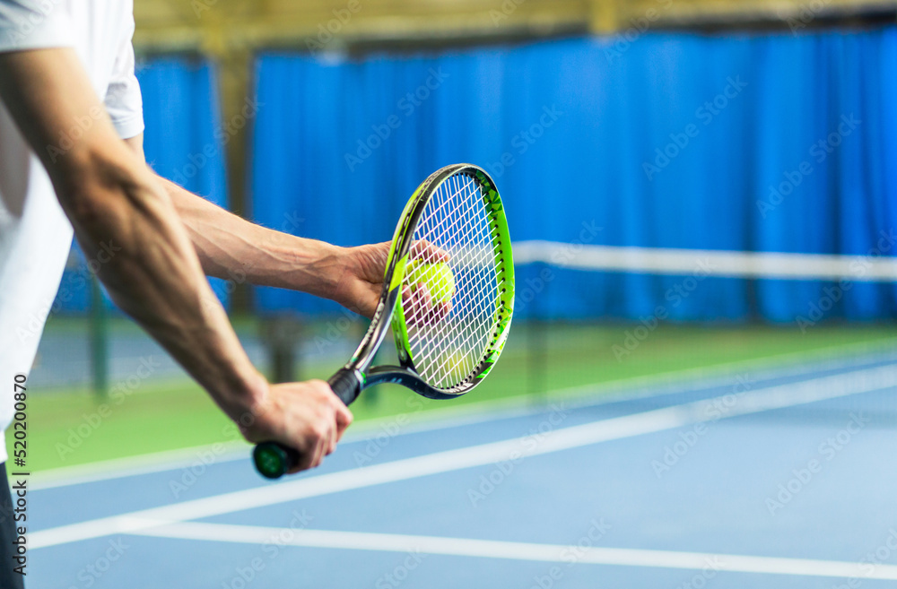 A man in a sports uniform holds a racket and a ball in his hands and is about to serve. Hands close up