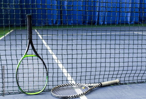 Tennis rackets against a stretched tennis net on an indoor tennis court © ribalka yuli