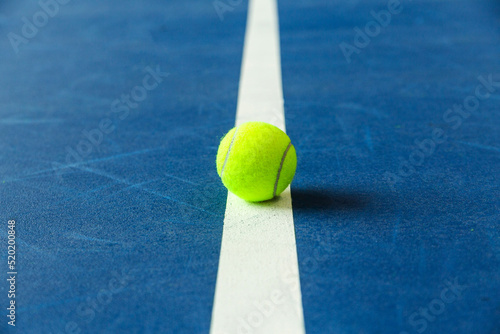 Summer sport concept with tennis ball on white line on hard tennis court blue color. Flat lay, top view, copy space, close up. © ribalka yuli