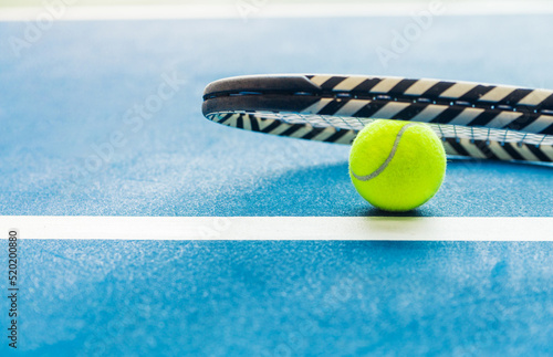 Racket and padel ball on blue court © ribalka yuli