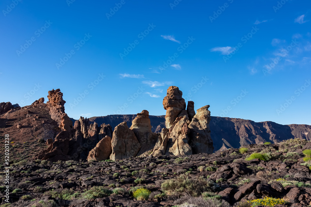 Scenic view on unique rock formation at Roques de Garcia, Mount Teide National Park, Tenerife, Canary Islands, Spain, Europe. Hiking trail over barren volcanic stone terrain. Blue sky background