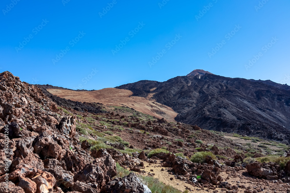 Solidified lava, ash and pumice on volcanic terrain. Black and brown dark sand and rocks on bare terrain. Scenic view on volcano Pico del Teide, National Park, Tenerife, Canary Islands, Spain, Europe