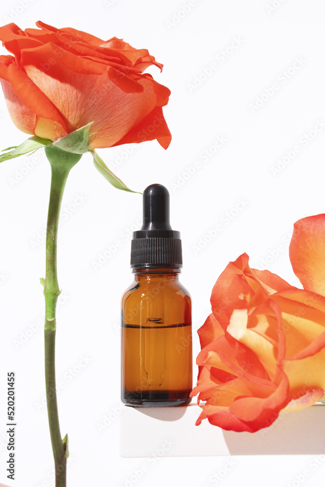 Glass dropper bottle on podium with rose flower. Hyaluronic acid oil, serum with collagen and peptides skin care product. Mockup packaging, cosmetic design branding Glass dropper bottle on podium with rose flower. Hyaluronic acid oil, serum with collagen and peptides skin care product. Mockup packaging, cosmetic design branding