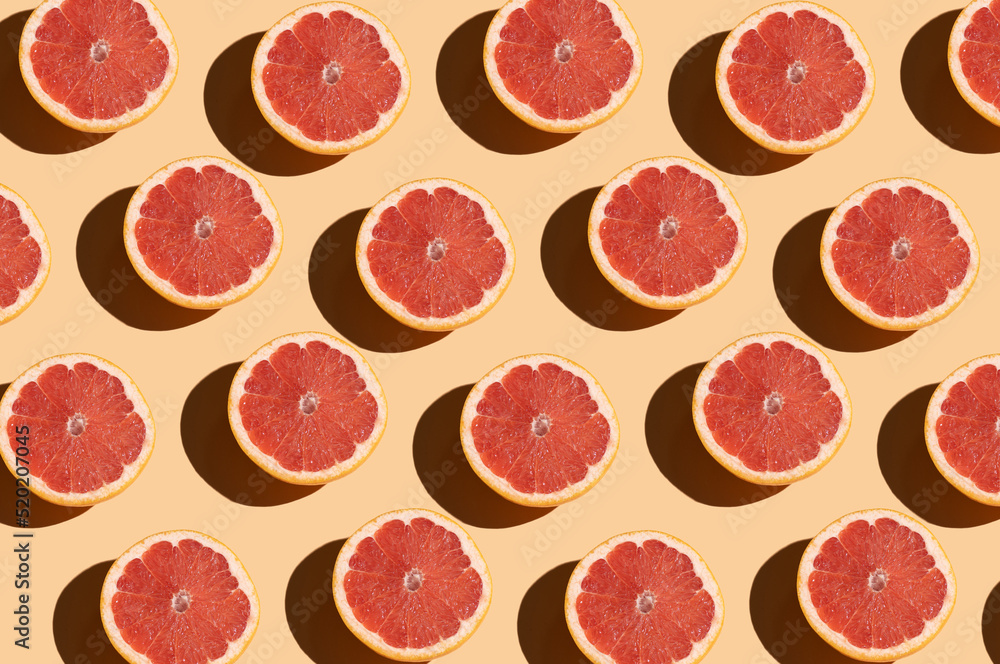 Grapefruit pattern on a beige background. Orange juicy grapefruit cut with shadow. Fruit food concept. Grapefruit pattern on a beige background. Orange juicy grapefruit cut with shadow. Fruit food concept.