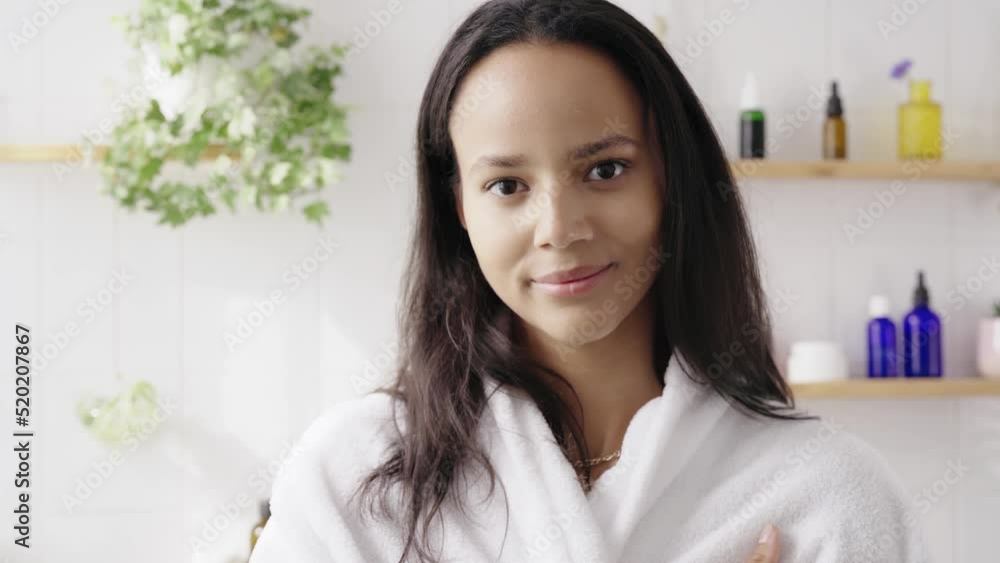 Portrait of young beautiful hispanic woman against white tiled wall wuth cosmetics. Smiling woman feeling calm and confident. Wellenss and natural cosmetics. 4K UHD Portrait of young beautiful hispanic woman against white tiled wall wuth cosmetics. Smiling woman feeling calm and confident. Wellenss and natural cosmetics. 4K UHD