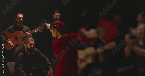 Beautiful stylish female artist dancing spanish style dance . Group of men playing on guitar and applauds to the dancer woman . Concept footage of spanish traditional culture . Waving cloth of skirt