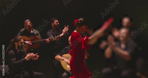 Beautiful stylish female artist dancing spanish style dance . Group of men playing on guitar and applauds to the dancer woman . Concept footage of spanish traditional culture . Waving cloth of skirt